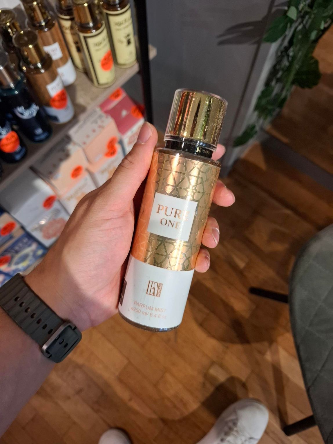 Een hand houdt een goud-witte fles 