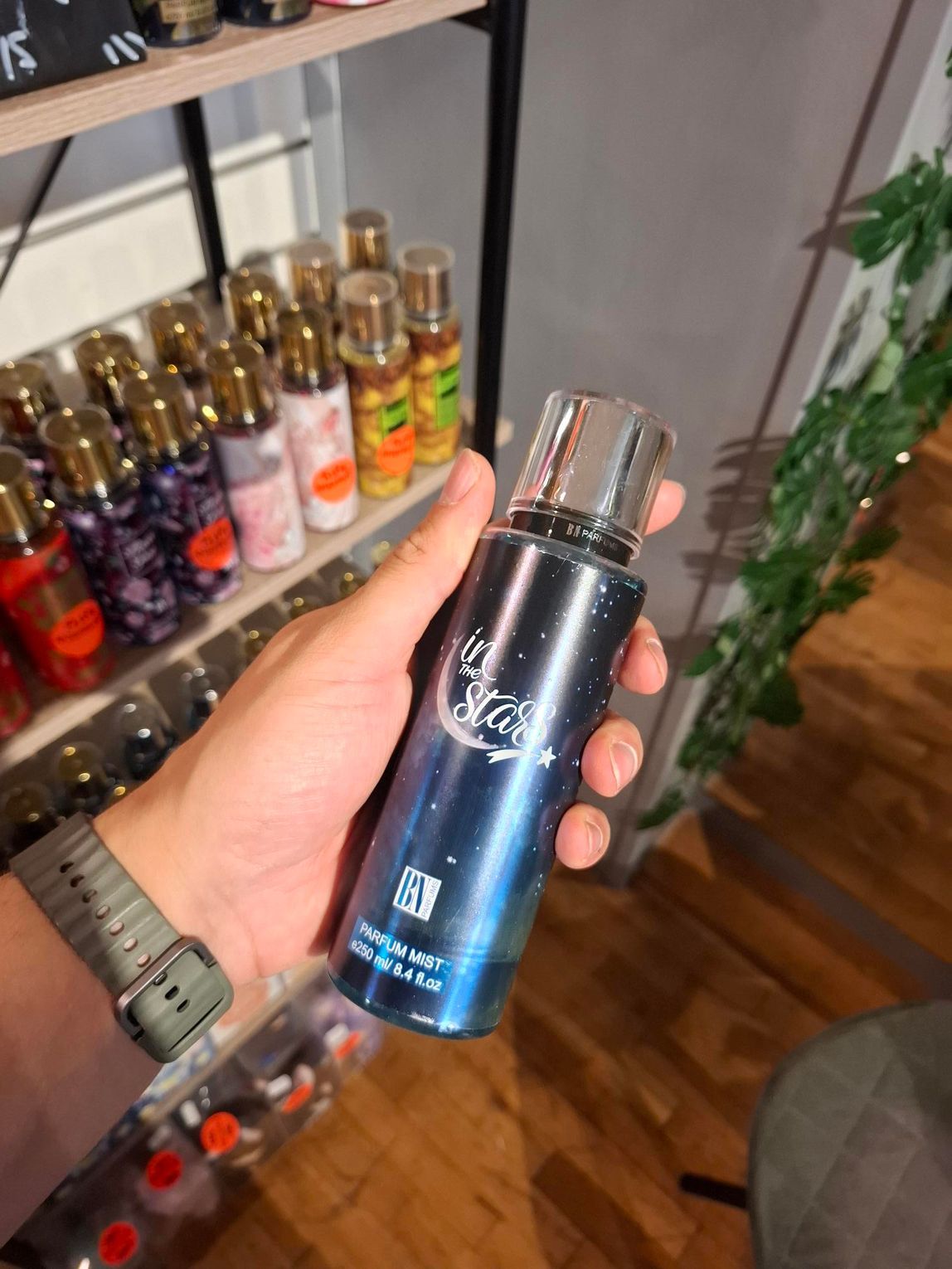 In een winkel houdt een hand een donkerblauwe fles 