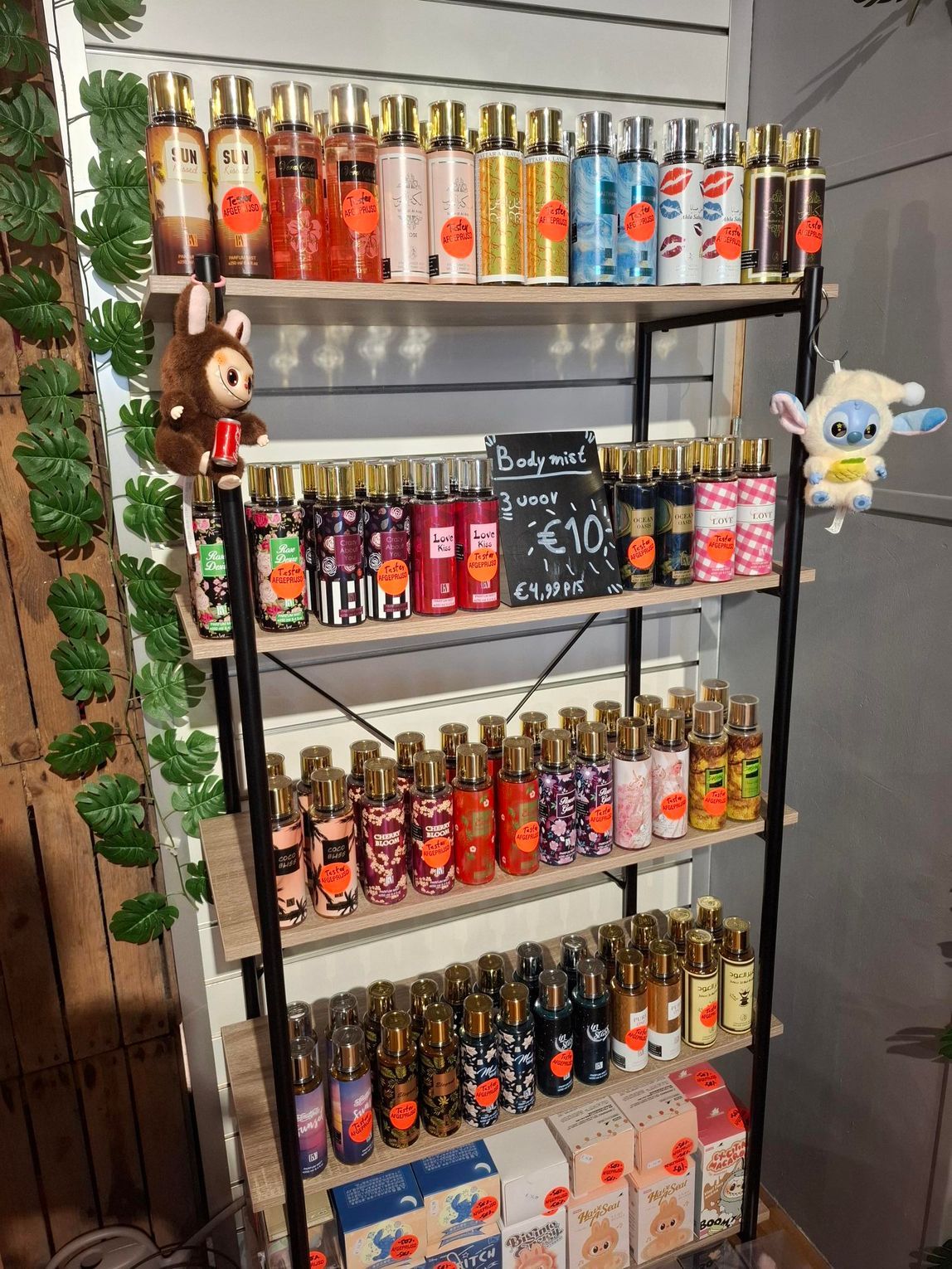 Een hand houdt een parfumverstuiver vast met een bloemenpatroon en zwarte en witte verticale strepen aan de onderkant.