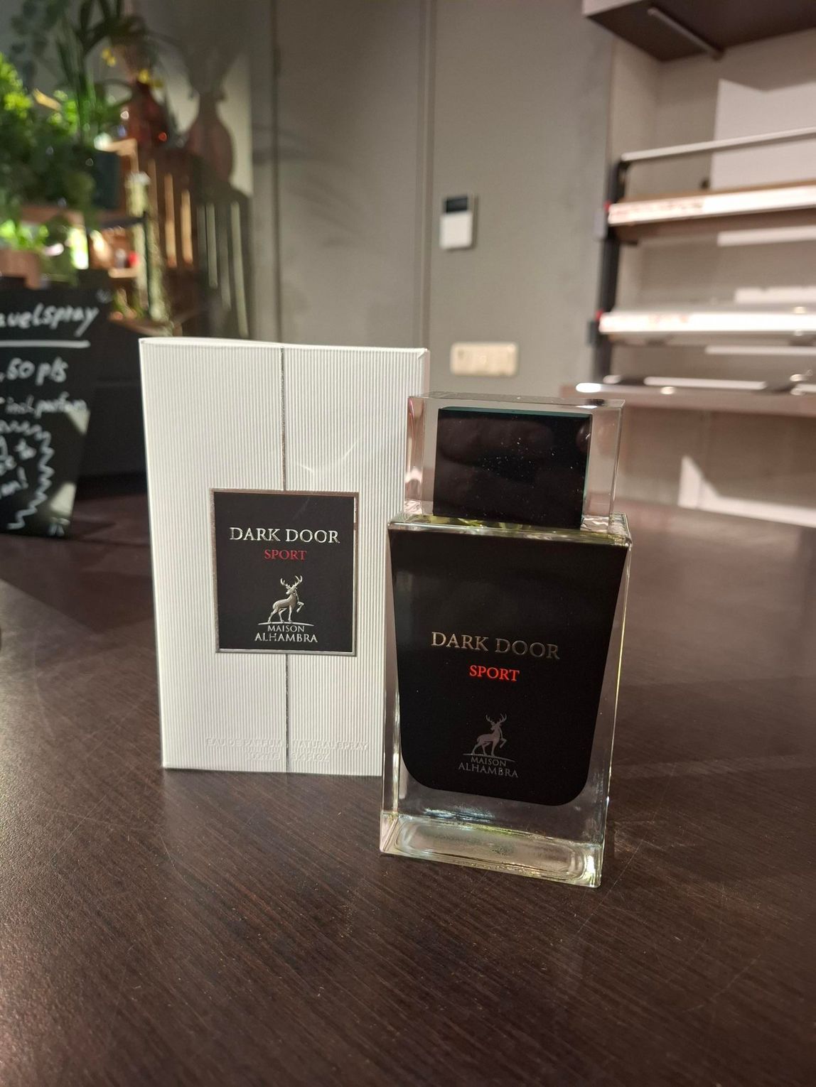 Een fles Dark Doge-parfum en de bijbehorende witgestreepte doos staan ​​op een donkerhouten oppervlak in een winkelomgeving.