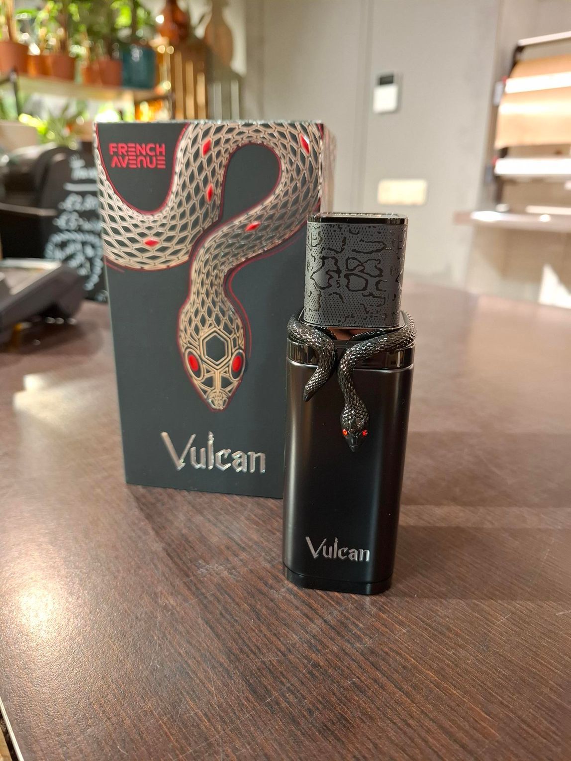 Een flesje Vulcan-parfum met een zwart slangenmotief, staand voor de bijpassende, geïllustreerde productverpakking.