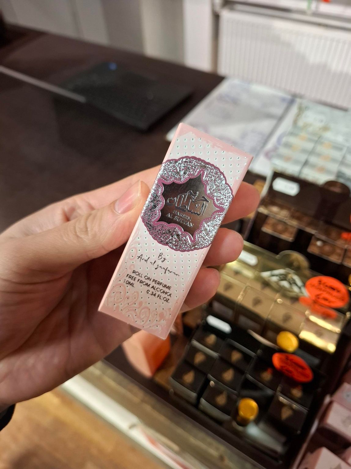 Een vitrine met diverse parfumflesjes en doosjes met parfum, voorzien van oranje prijskaartjes, op een houten toonbank.