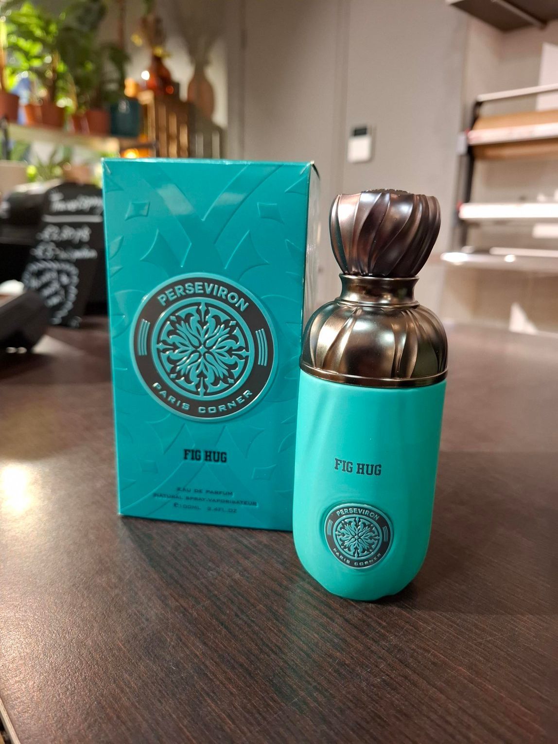 Een turquoise parfumdoosje met bijpassend flesje en metalen dop, staand op een houten ondergrond.