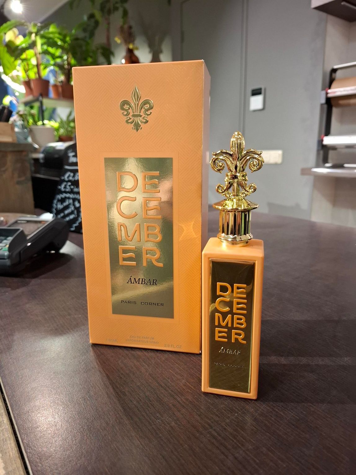 Een rechthoekige, perzikkleurige parfumdoos met bijpassende flacon, voorzien van het opschrift 