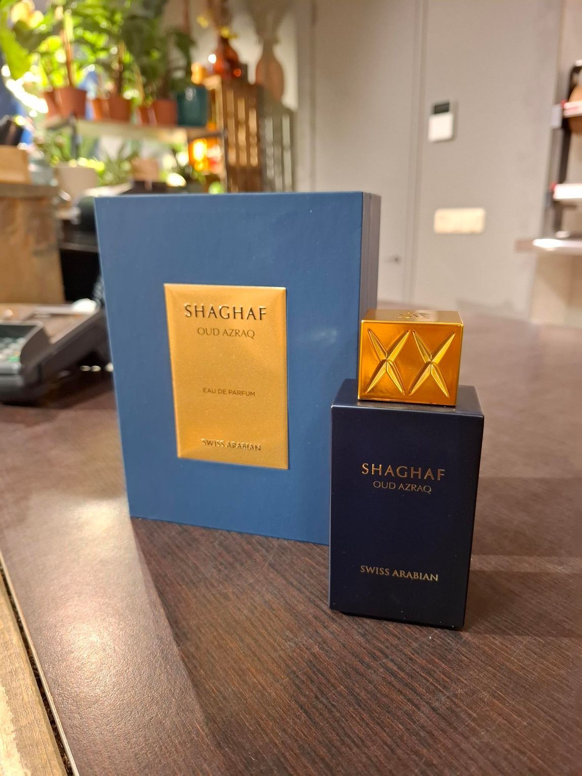 Een donkerblauwe rechthoekige parfumfles met een gouden dop en een bijpassende blauwe doos, beide met het opschrift 