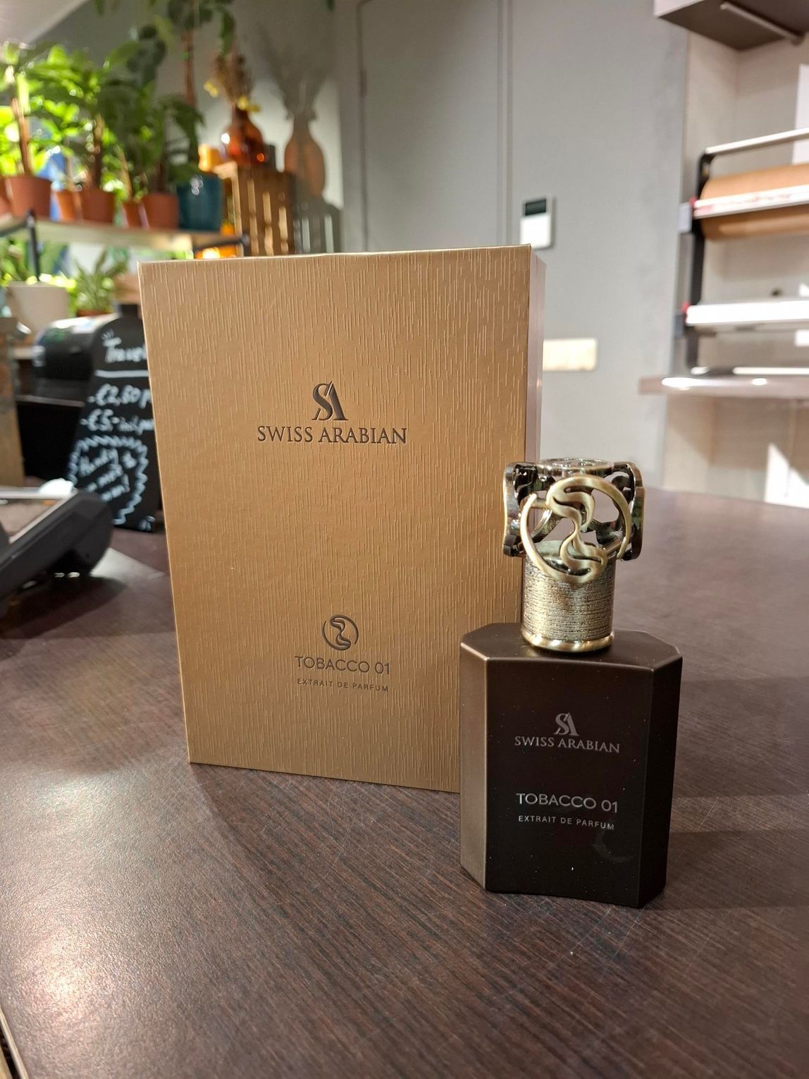 Een fles Paco Rabanne Phantom-parfum staat voor de houten presentatiedoos op een tafel.