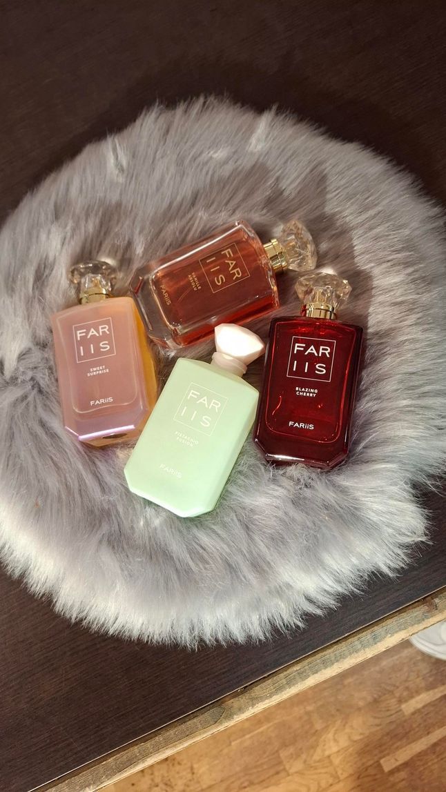 Vier flesjes Kayali-parfum in verschillende kleuren staan ​​uitgestald op een rond, grijs kleed van imitatiebont.