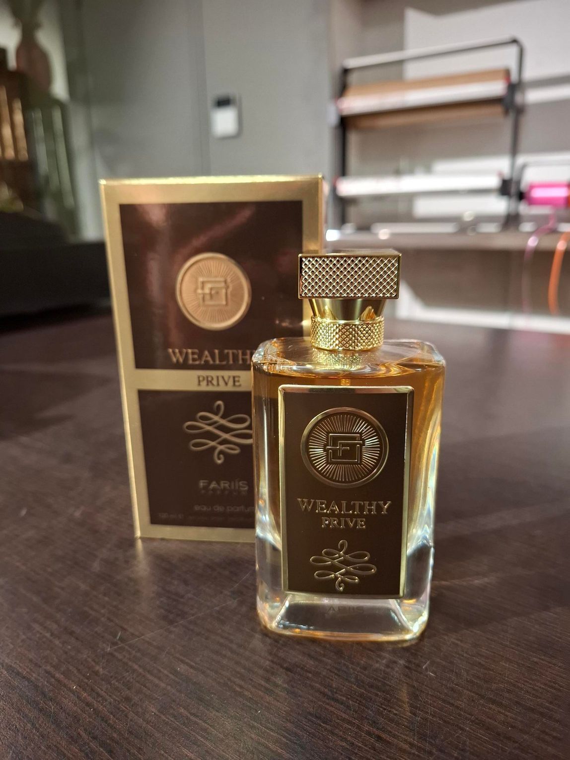 Luxe parfumflesje met gouden dop naast de bijpassende doos op een donker aanrecht.
