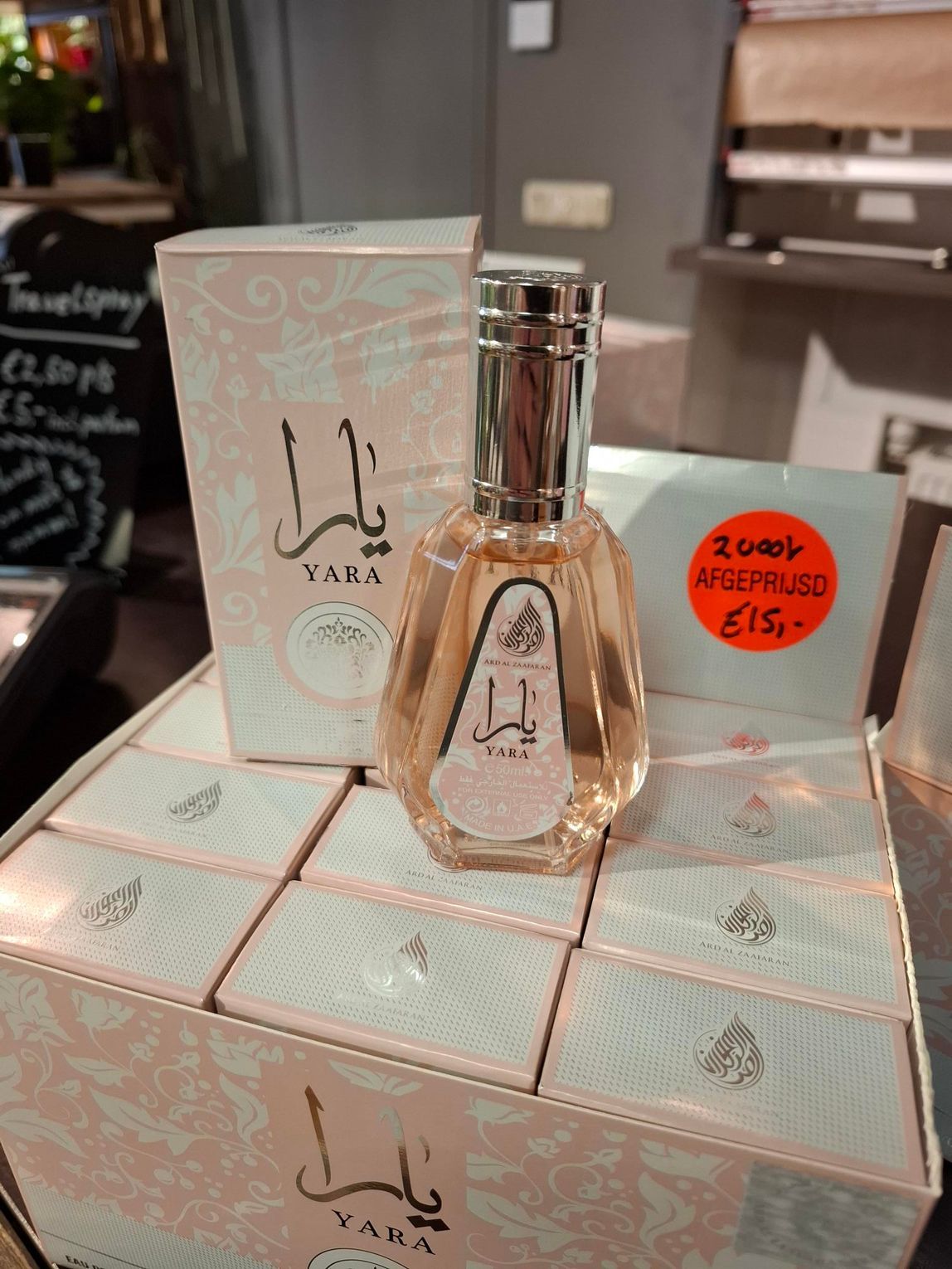 Het flesje en doosje van Yara-parfum staan ​​op een pastelroze geschenkverpakking met een rode kortingssticker.