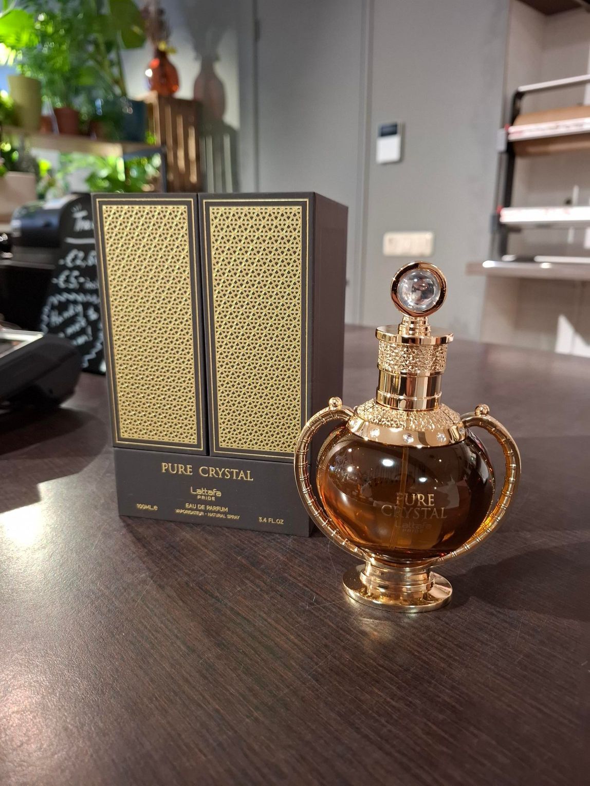 Een sierlijk gouden parfumflesje staat naast een zwart-gouden parfumdoos op een tafel.