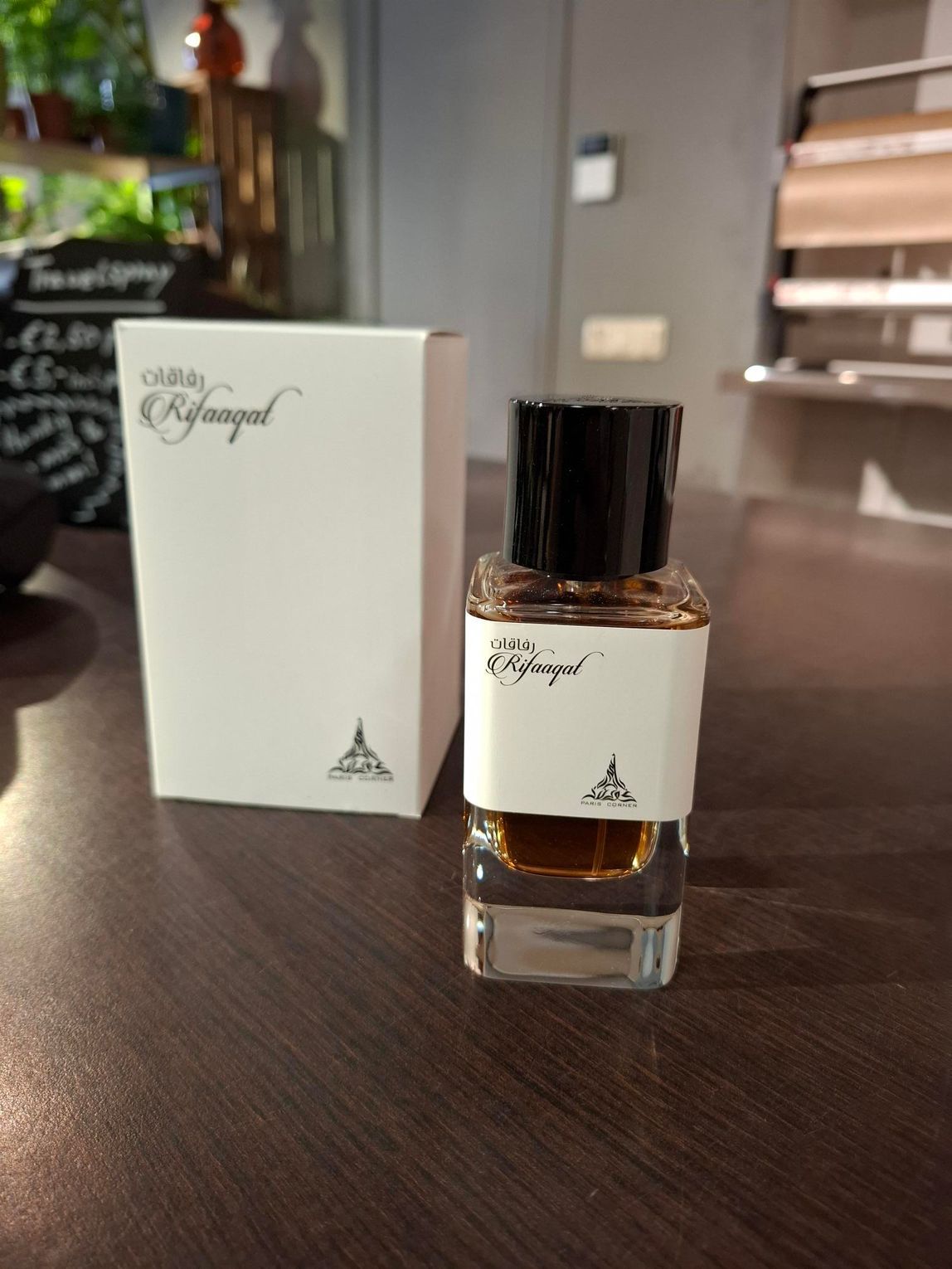 Parfumflesje en bijpassend doosje op een donkerhouten tafel in een zacht verlichte kamer.