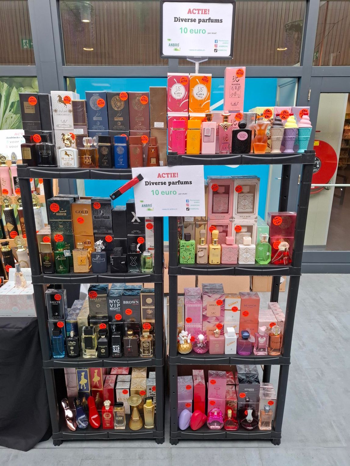 Het flesje en doosje van het parfum Pink Dahlia staan op een donkere tafel in een lichte kamer.