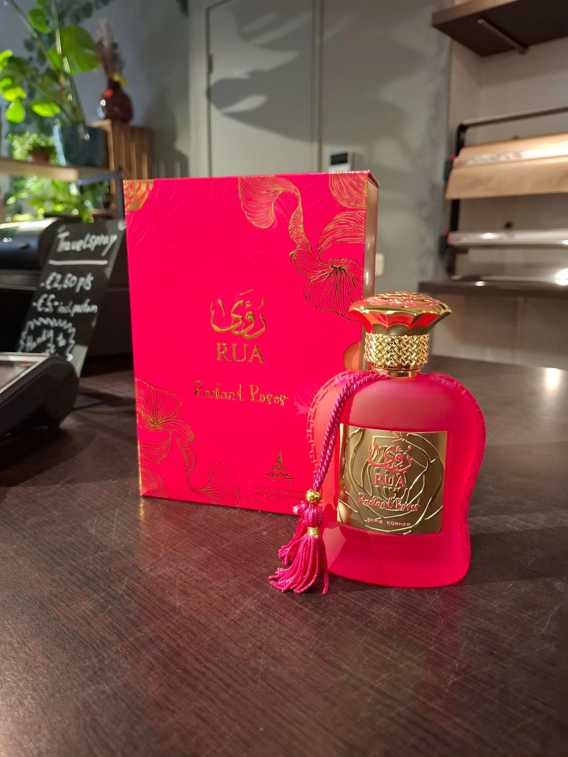 Roze parfumflesje met bijpassend doosje op een toonbank in een winkelvitrine.