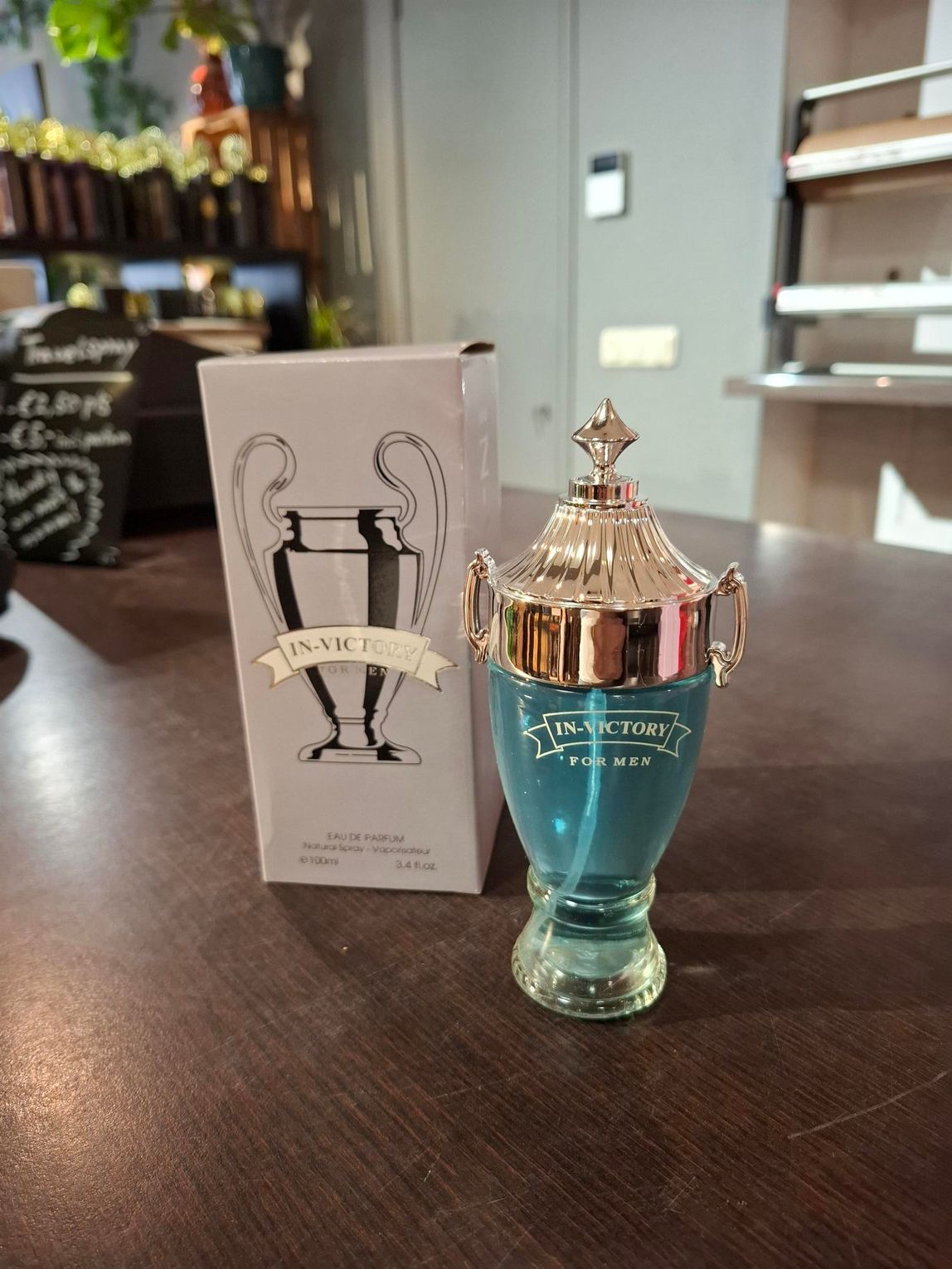 Blauwe parfumfles met sierlijke gouden dop naast de doos op een tafel in een winkel.