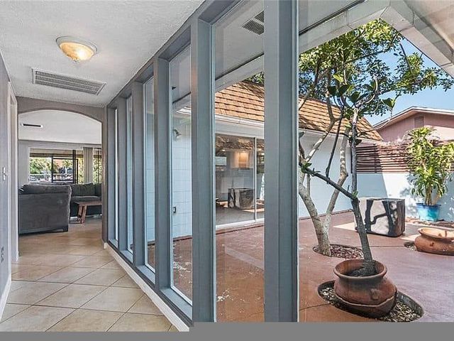 Interior hallway with windows looking onto a patio with a tree in a pot.