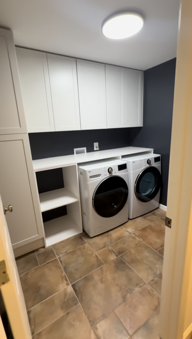 Laundry room with white cabinets, dark blue wall, washer, dryer, shelf, and brown tile flooring.