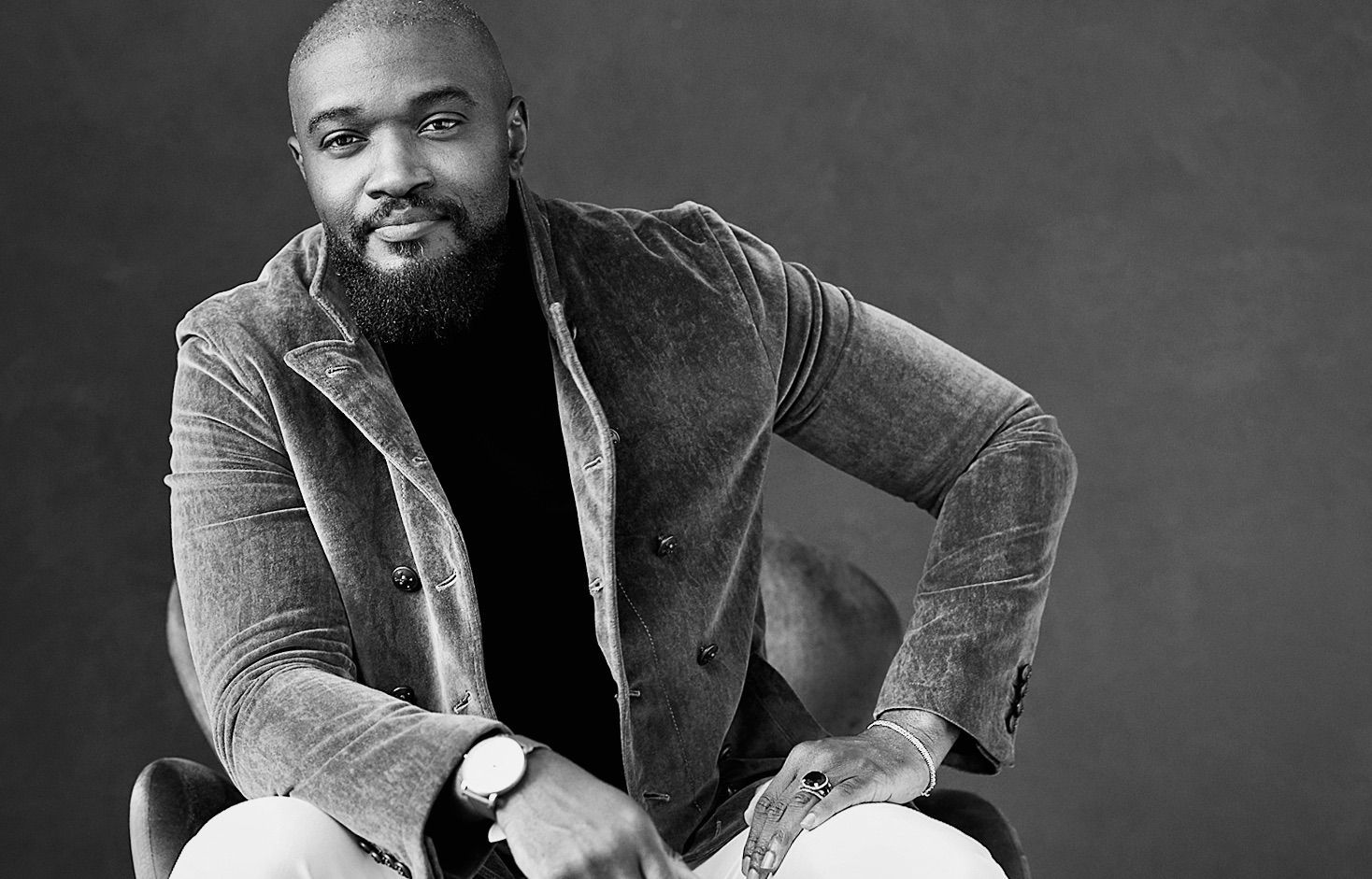 Dr Ola in velvet blazer and turtleneck, seated, looking at camera.