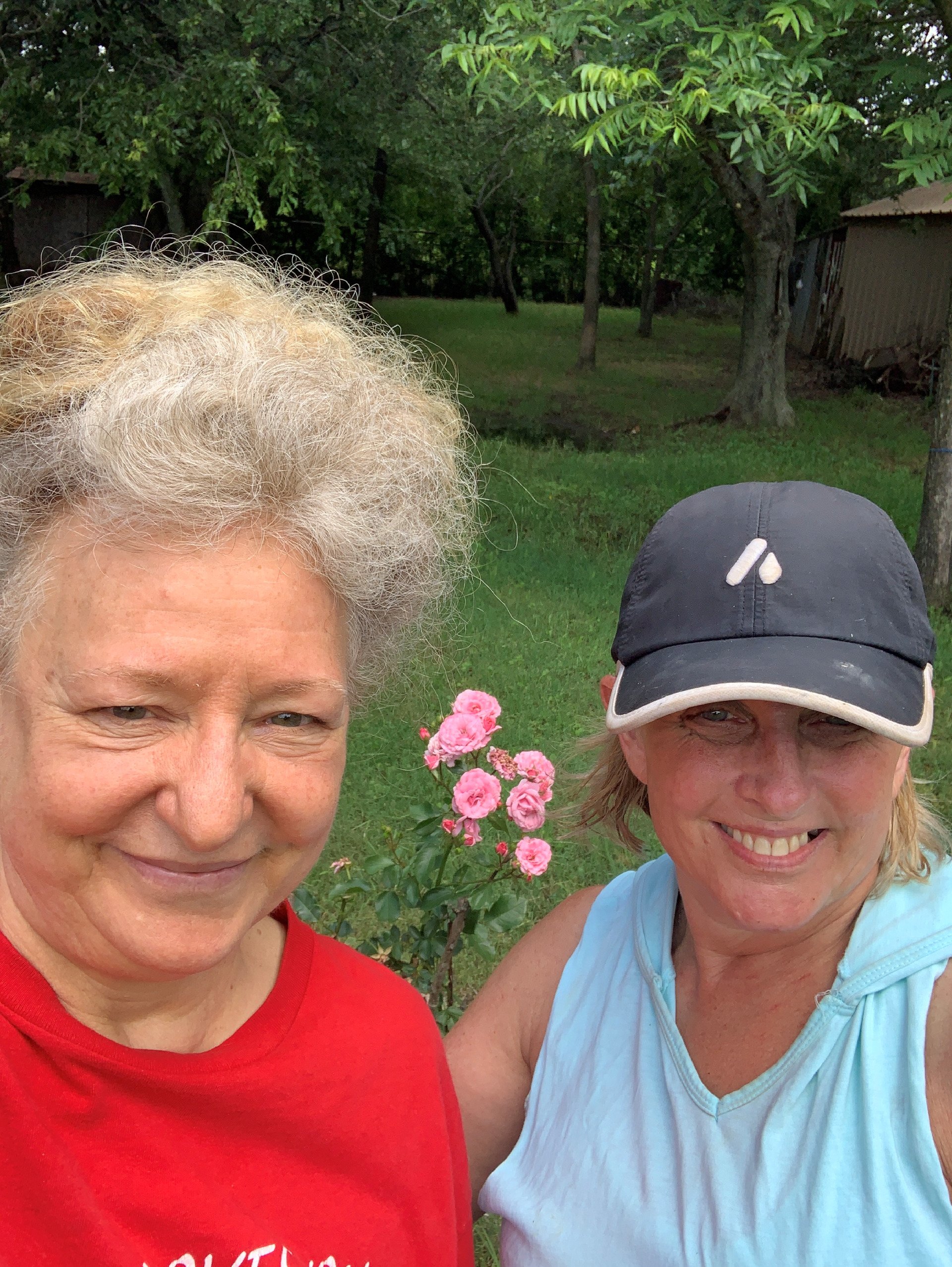 two women are posing for a picture in a garden .