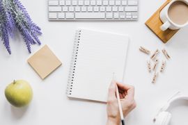 a person is writing in a notebook on a desk .