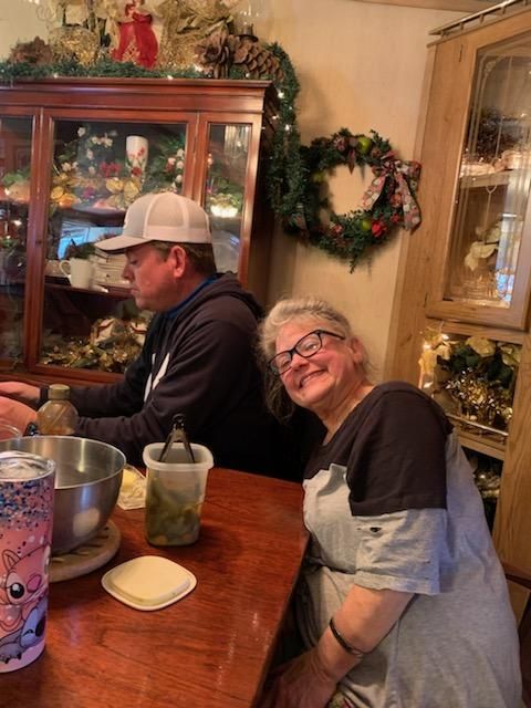 a man and a woman are sitting at a table with a wreath on the wall behind them .