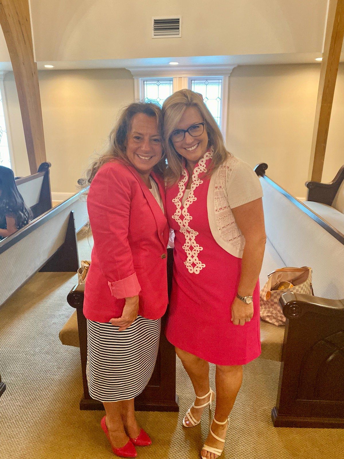 two women in pink dresses are posing for a picture in a church .