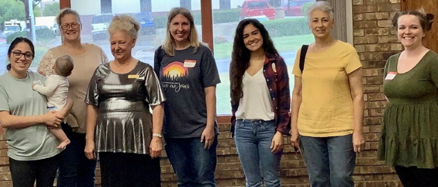 a group of women are standing next to each other in front of a window .