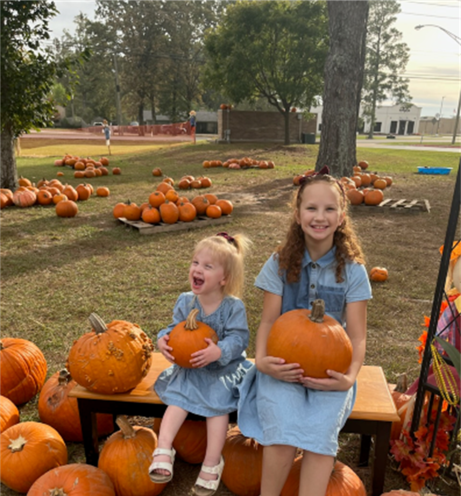 two little girls are sitting on a bench holding pumpkins