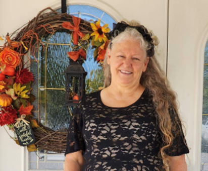 a woman in a black lace top is standing in front of a wreath .