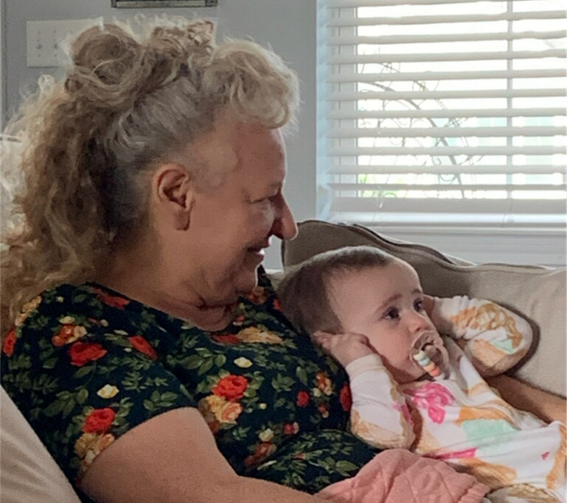 a woman is sitting on a couch holding a baby with a pacifier in her mouth .