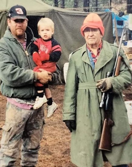 memories; hunting; man holding shotgun and other man holding baby