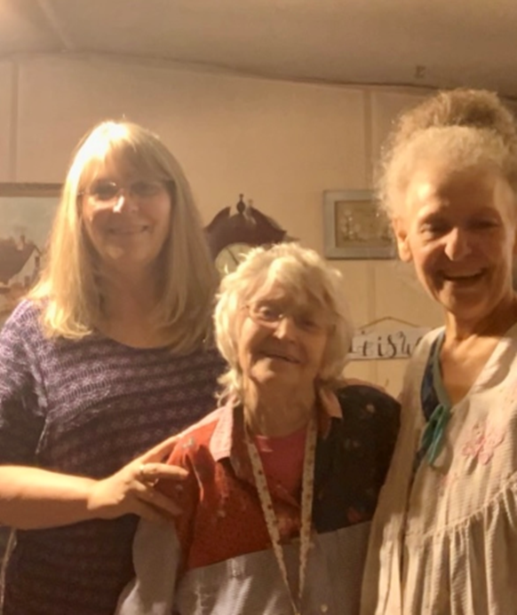 Three women are posing for a picture in a room with a sign that says brisa on it