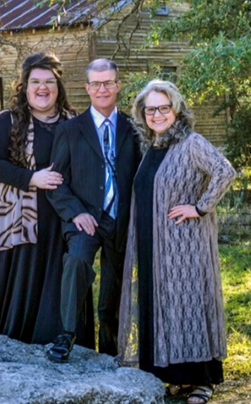 a man and two women are posing for a picture while standing next to each other on a rock .