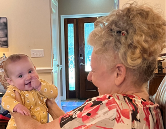 an elderly woman is holding a baby in her arms .