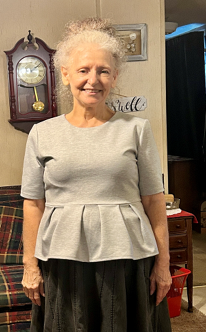 A woman is standing in a living room in front of a clock.