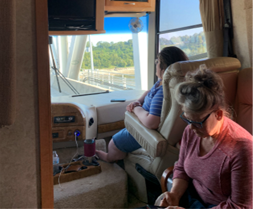 two women are sitting in a rv looking at their phones