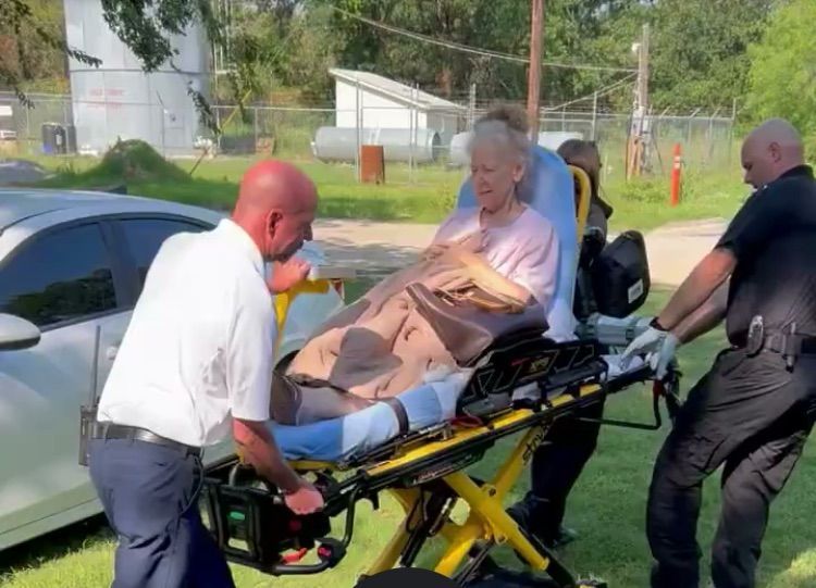 lady on stretcher and 2 men assisting 