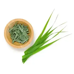 A wooden bowl filled with green leaves next to a bunch of green leaves.