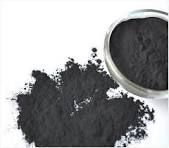 A pile of black powder next to a metal bowl on a white surface.