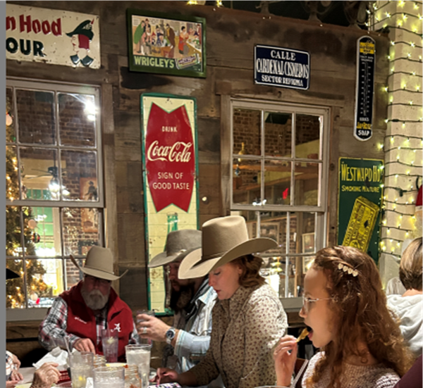 a group of people are sitting at a table in front of a coca cola sign