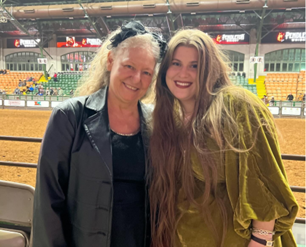 two women are posing for a picture at a rodeo .