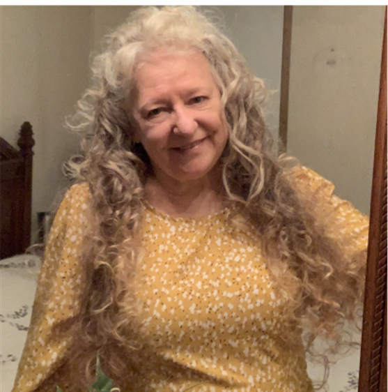 a woman with long curly hair is smiling in front of a mirror