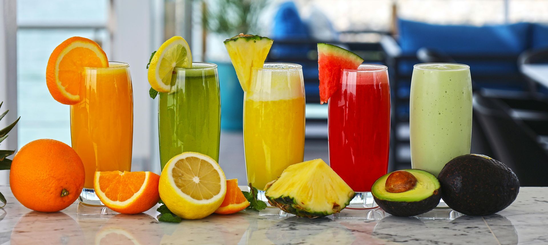 Assorted colorful fruit juices and sliced citrus with whole fruits on a table outdoors