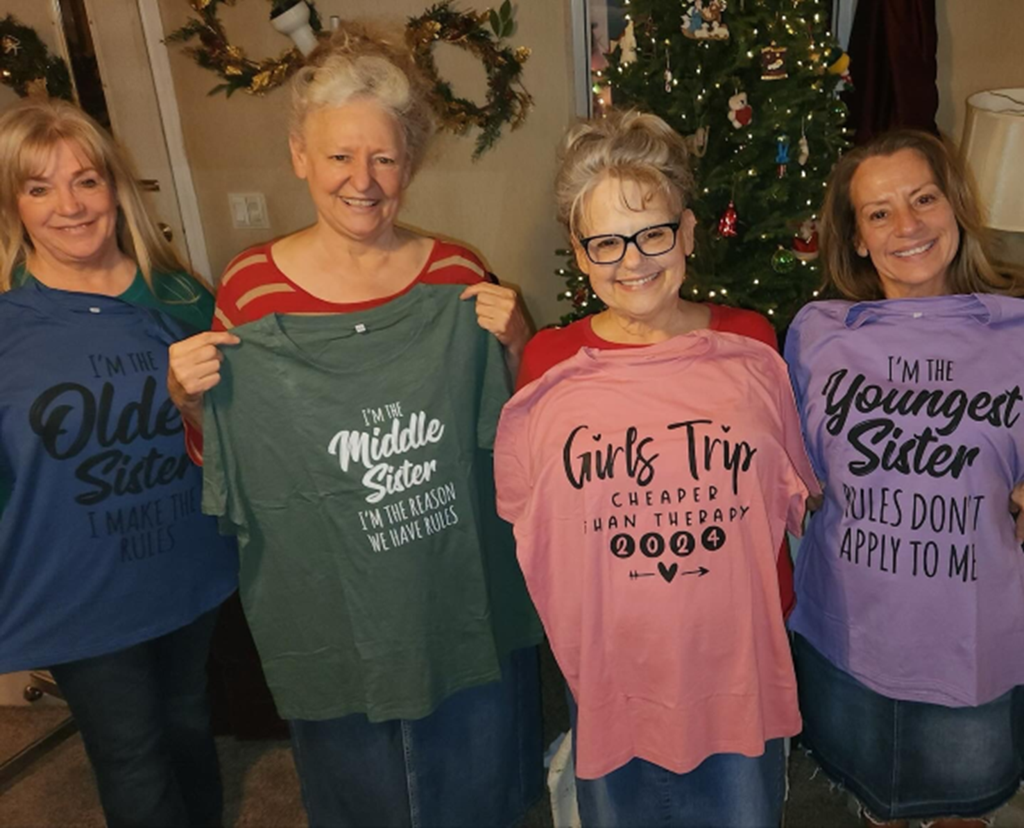 a group of women holding up t-shirts one of which says i 'm the youngest sister
