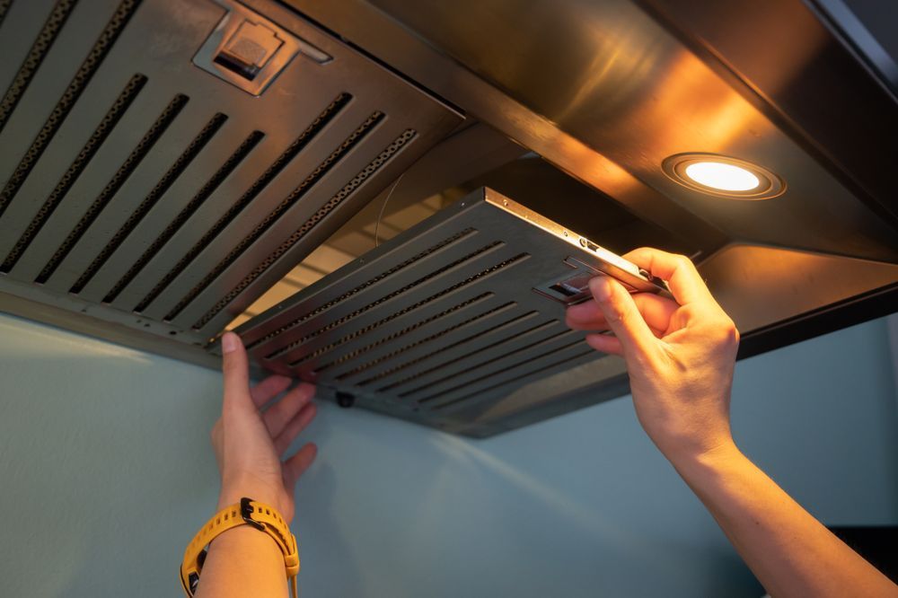 A person is cleaning a stainless steel hood in a kitchen.