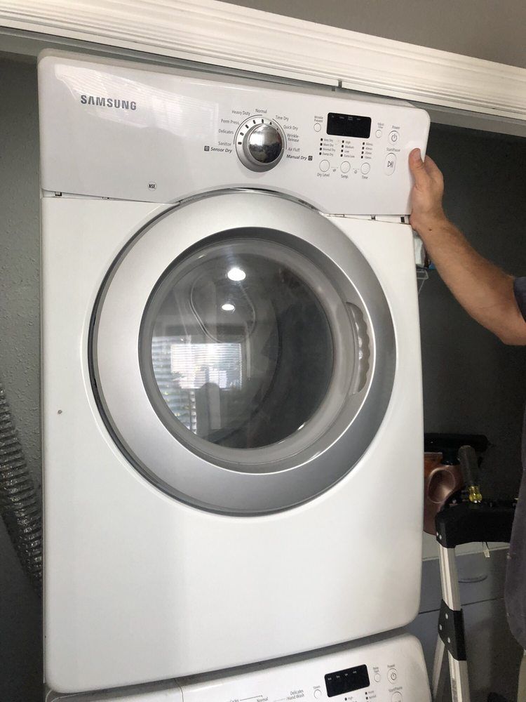 A white samsung washer and dryer are stacked on top of each other.