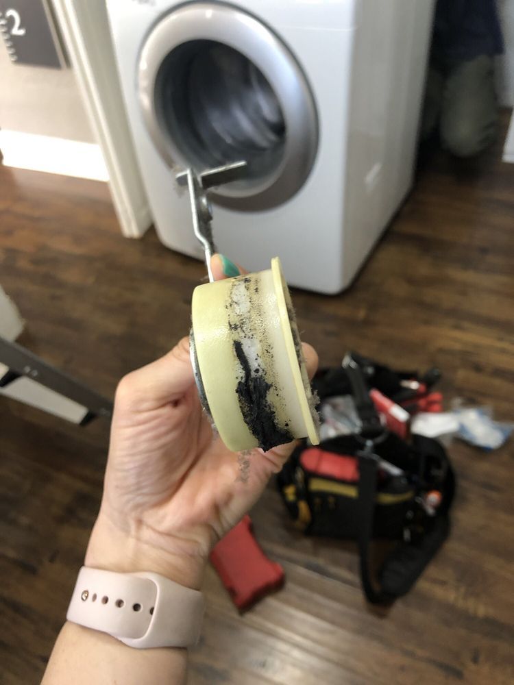 A person is holding a piece of tape in front of a washing machine