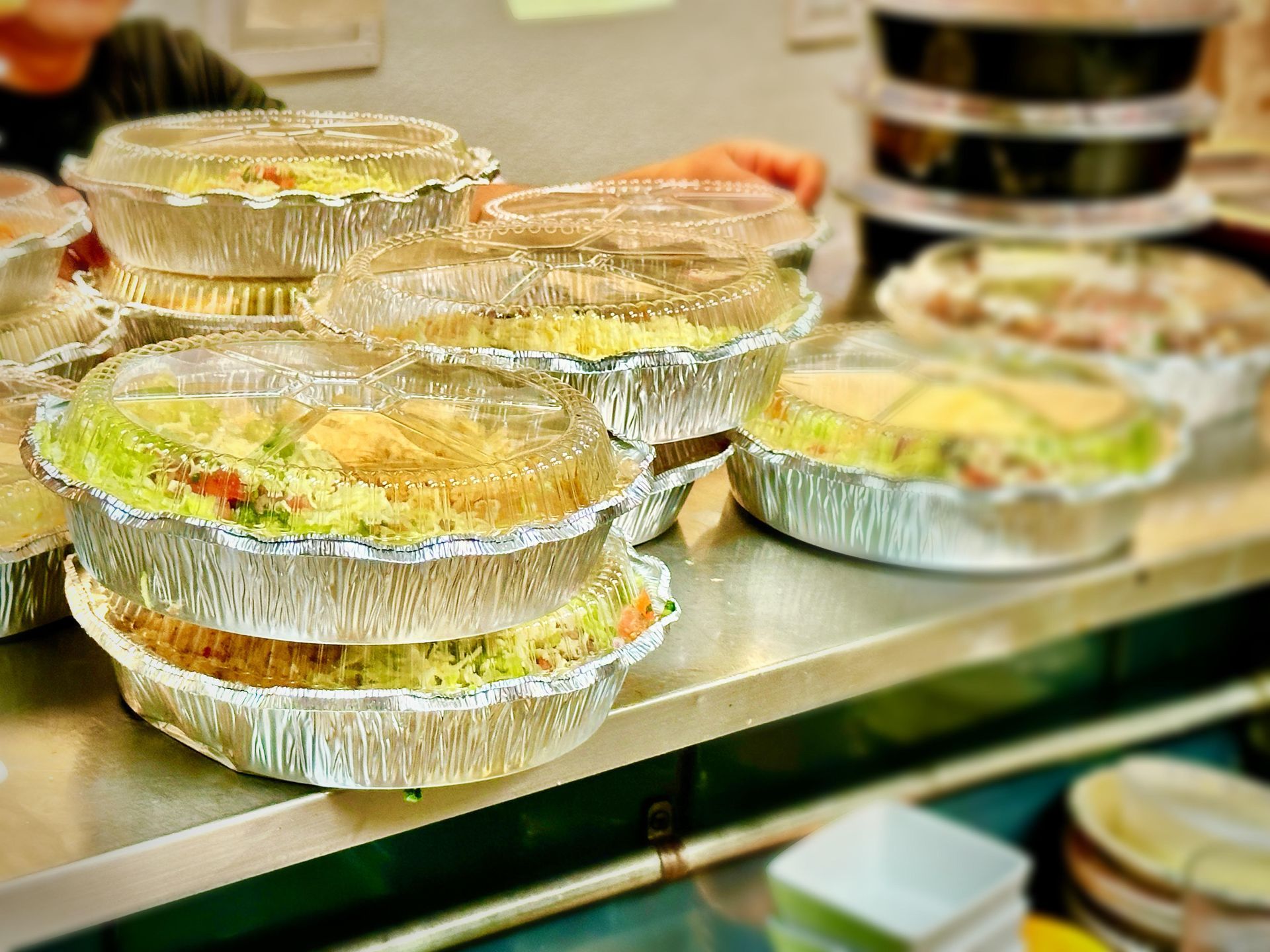 Prepared food containers stacked on a metal surface, ready for service.