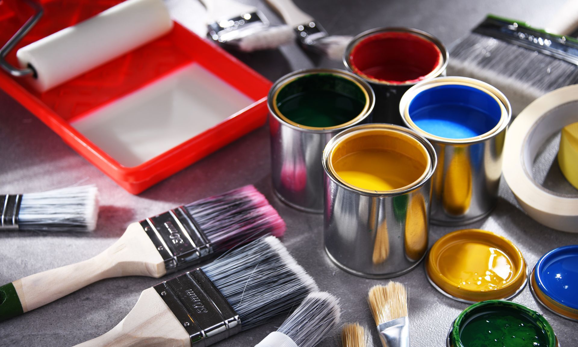 Paint cans and brushes with a paint tray and roller.