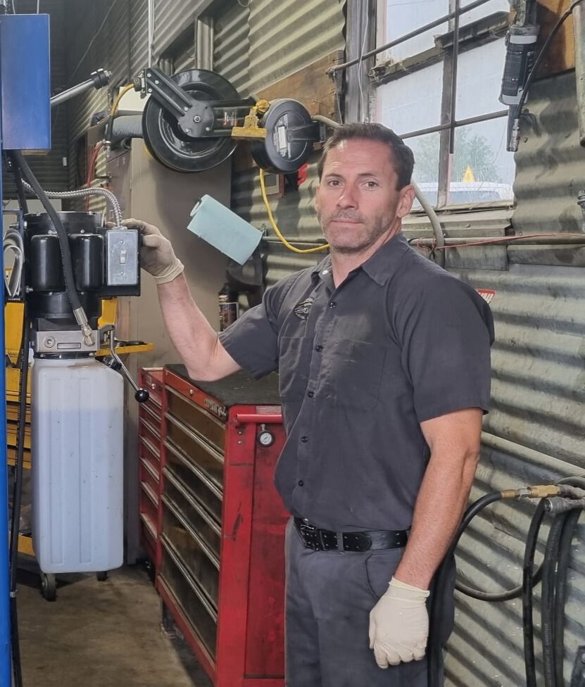 Team Member Sitting Outdoors Near Truck | Cole's Auto Repair & Service