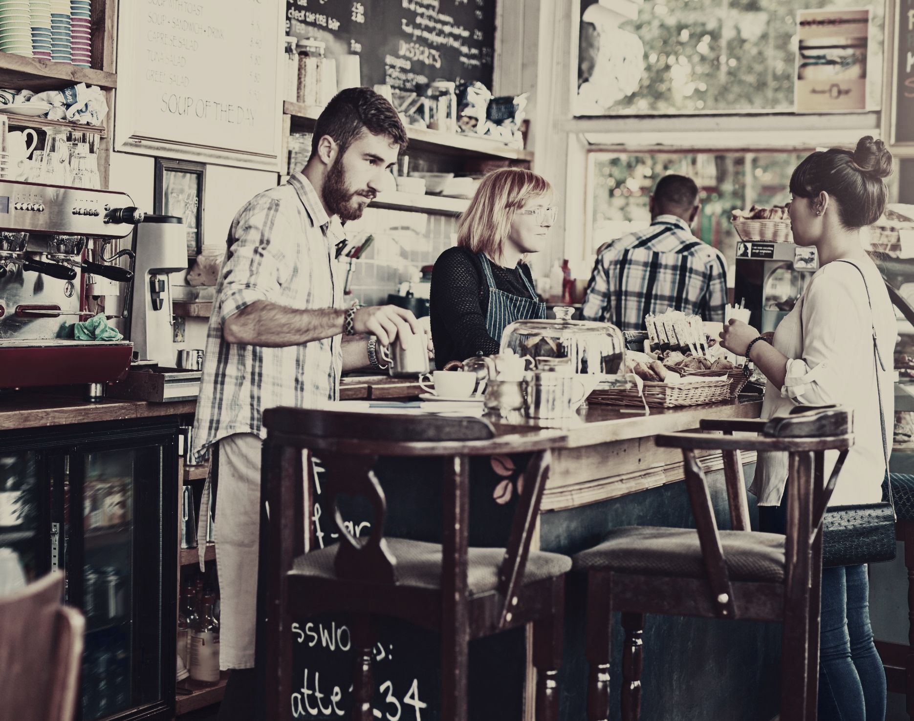 A group of people are sitting at tables in a coffee shop.